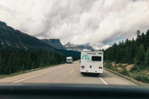 Campervans driving on a scenic mountain road surrounded by forests